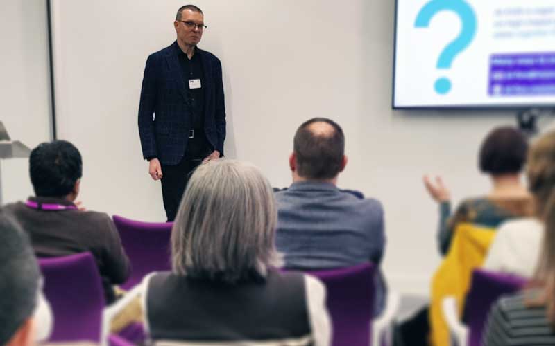 Man stood presenting to a seated audience